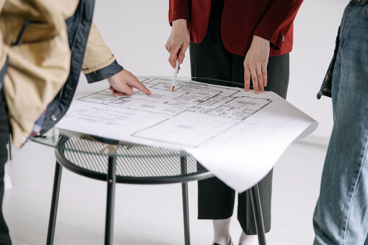 home-services-02 A group of people reviewing architectural blueprints on a table indoors.